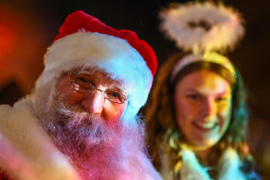 A man dressed as Santa Claus sits next to a woman dressed as an angel.