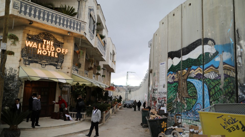 People stand outside the Walled Off hotel, which was opened by street artist Banksy, in the West Bank city of Bethlehem.