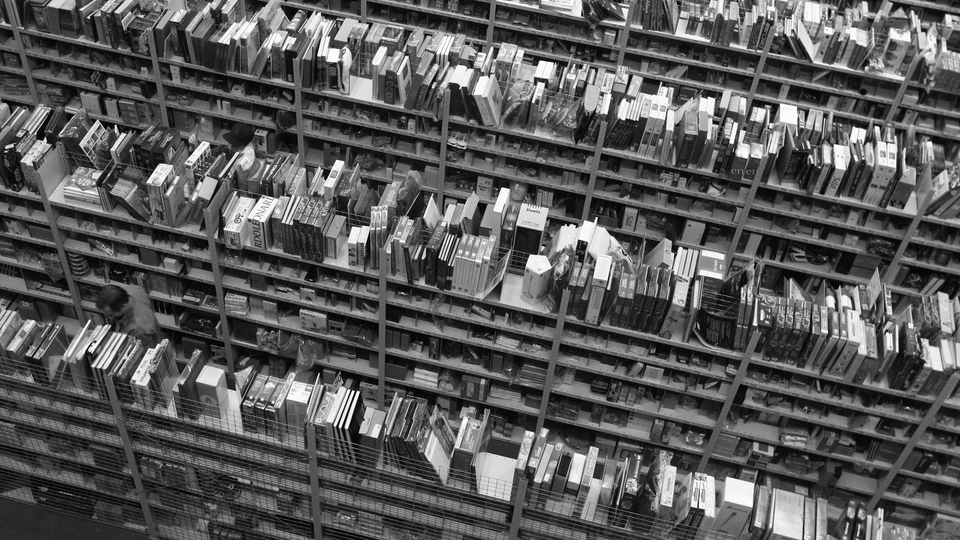 A black and white photo showing shelves of books.