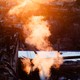 A color photograph of smoke rising in orange light above burned homes.