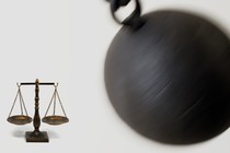 An image of a wrecking ball about to hit the scales of justice