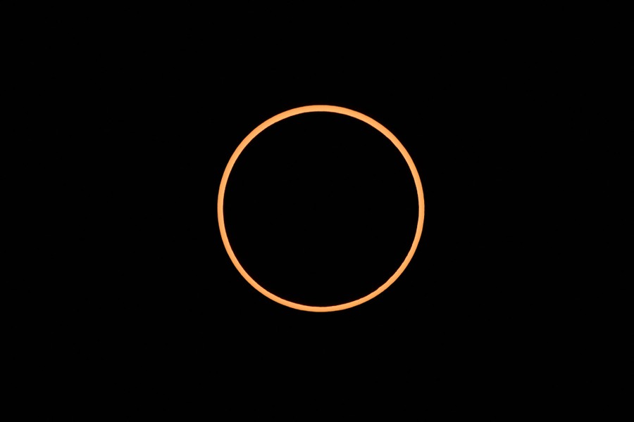 The sun, eclipsed by the moon, looking like a thin circle in a dark sky