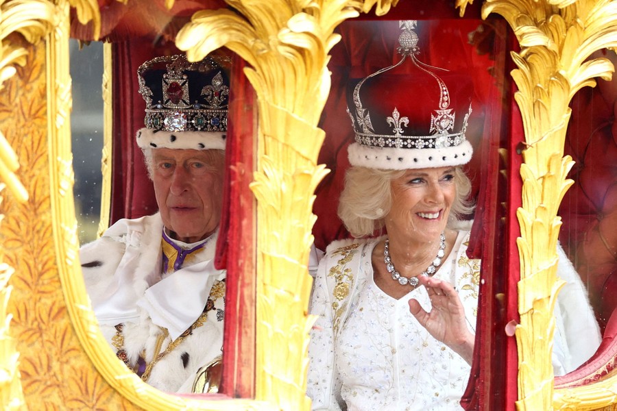 King Charles and Queen Camilla ride in a gold carriage.