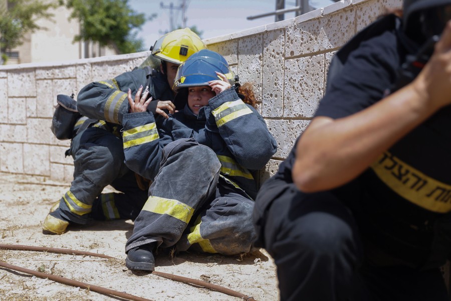 Several people take cover outside, crouching low behind a short wall.