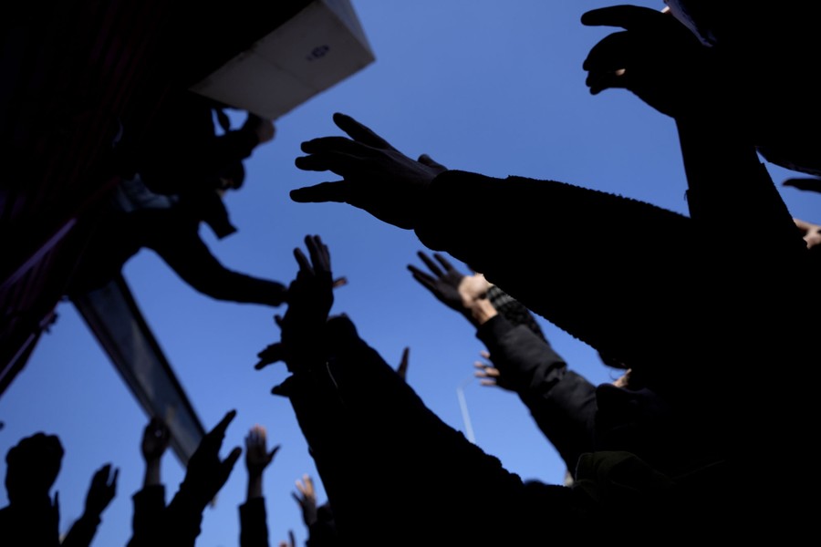 A view looking up showing outstretched arms of people reaching for aid distribution