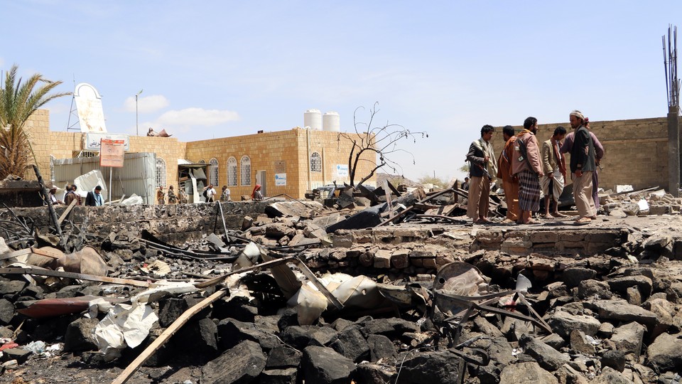 People stand at the scene of an air strike in Saada, Yemen on March 28, 2019.