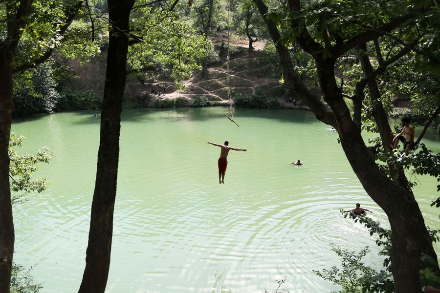 A person falls toward the surface of a lake after letting go of a rope swing.