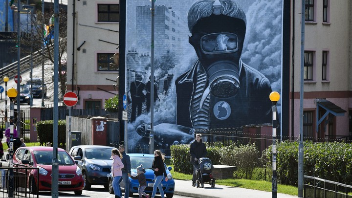 Pedestrians walk past a mural in Derry, Northern Ireland.
