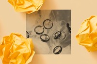 A black-and-white photo shows several shiny wedding bands displayed on a marbled surface.