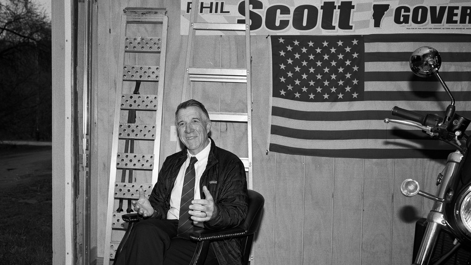 Governor Phil Scott in a garage with an American flag and a motorcycle