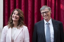 Bill and Melinda Gates smile broadly in front of a red curtain.