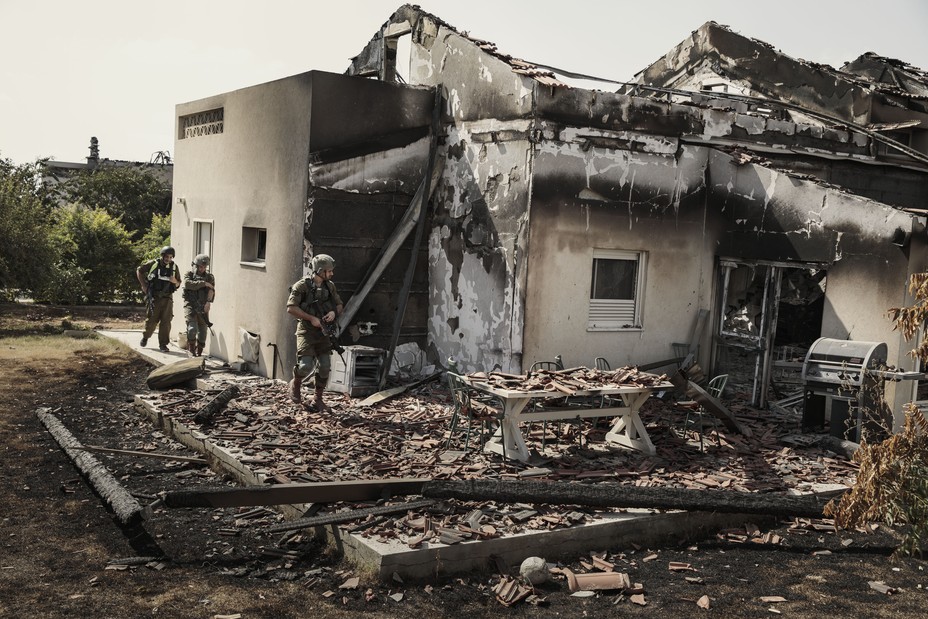 Soldiers wal through the ruins of a burned home.