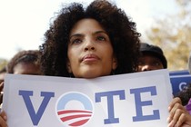 A woman holding a "Vote" sign with the Obama campaign logo as the "o"