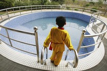 A young boy looks out at a big pool