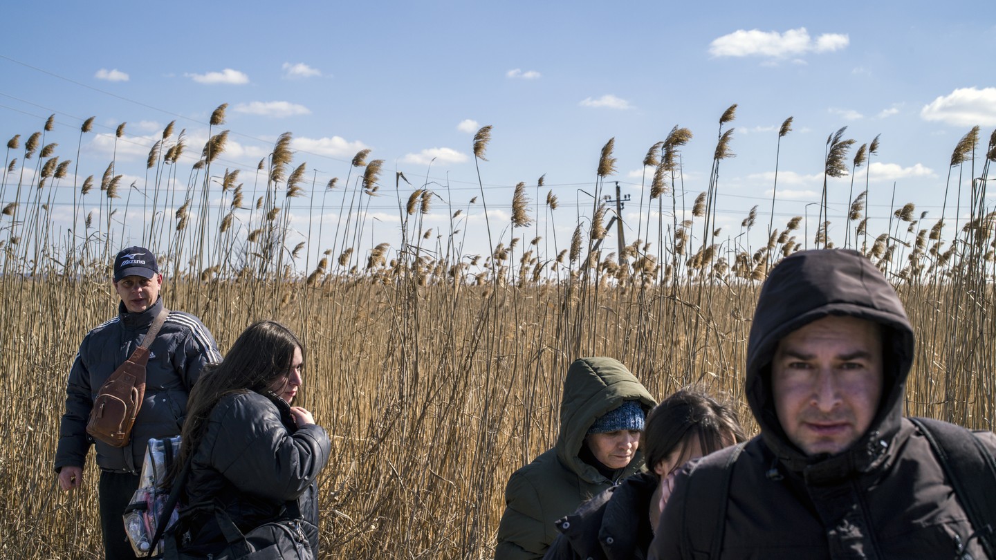 Ukrainian refugees in winter coats in front of a field