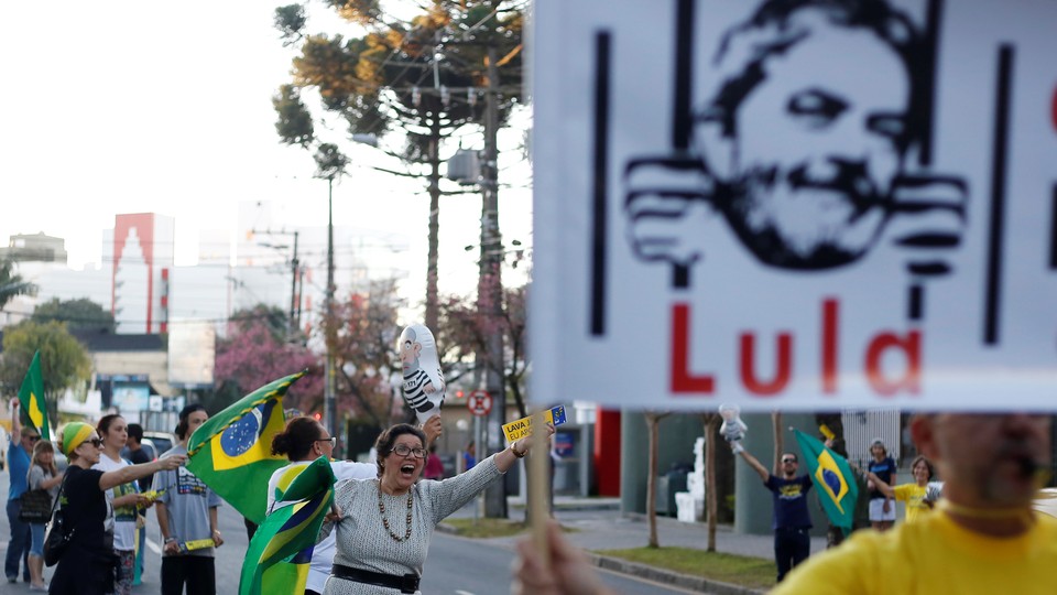 People celebrate and hold up a sign of former president Lula da Silva behind bars.