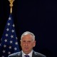 James Mattis stands in front of a black background and an American flag.