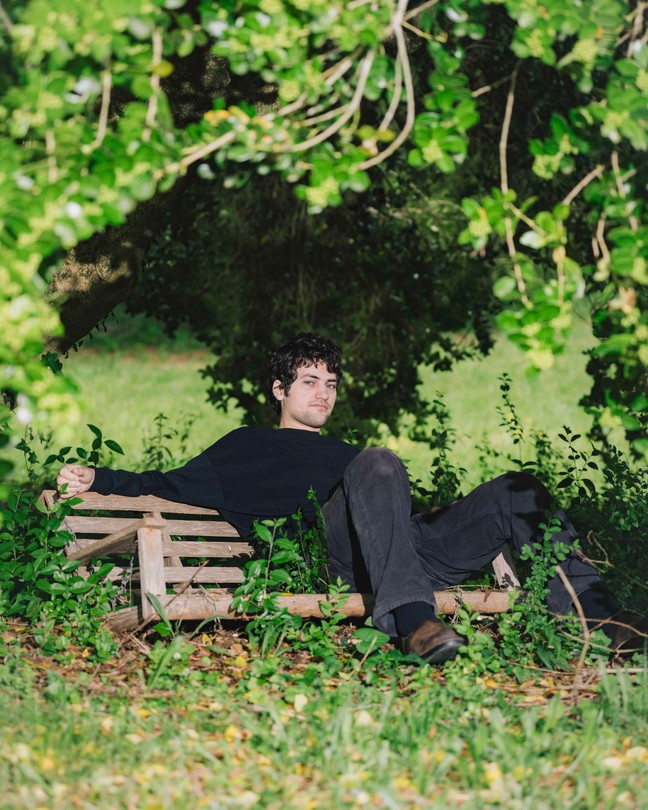 The guitarist MJ Lenderman, sitting on a bench