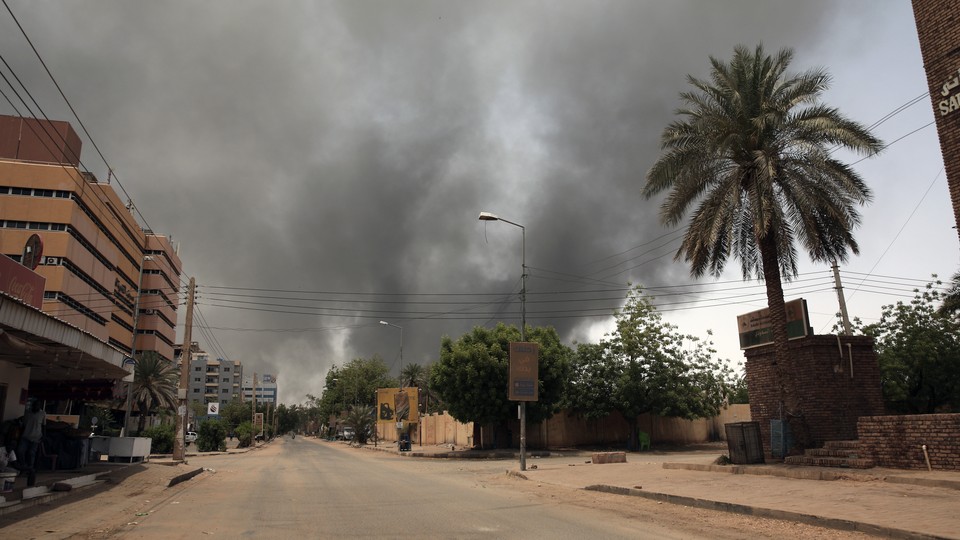 Picture of desolate urban street in Sudan, clouds of smoke in visible in the background
