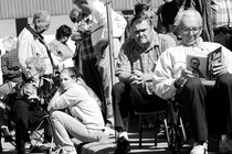 A crowd of people sitting and standing on a curb