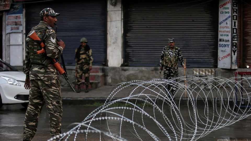 Indian security forces stand near concertina wire.