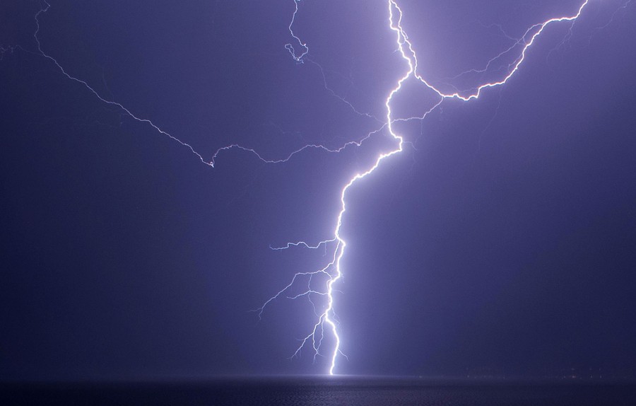 A bolt of lightning strikes the sea at night.