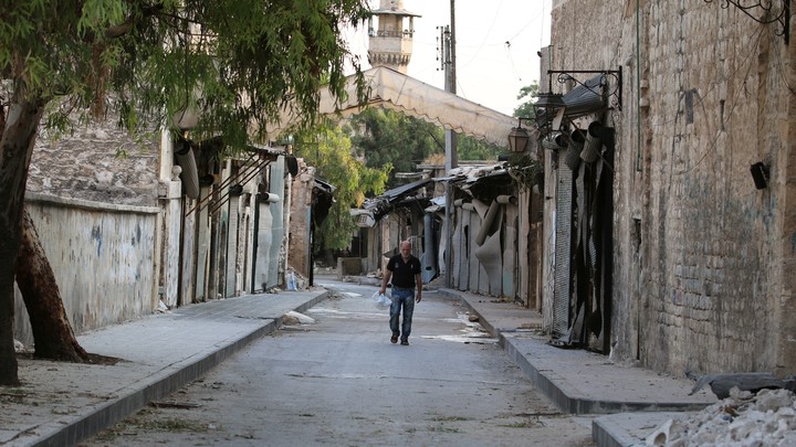 A man walks near damaged shops in the Syrian city of Aleppo