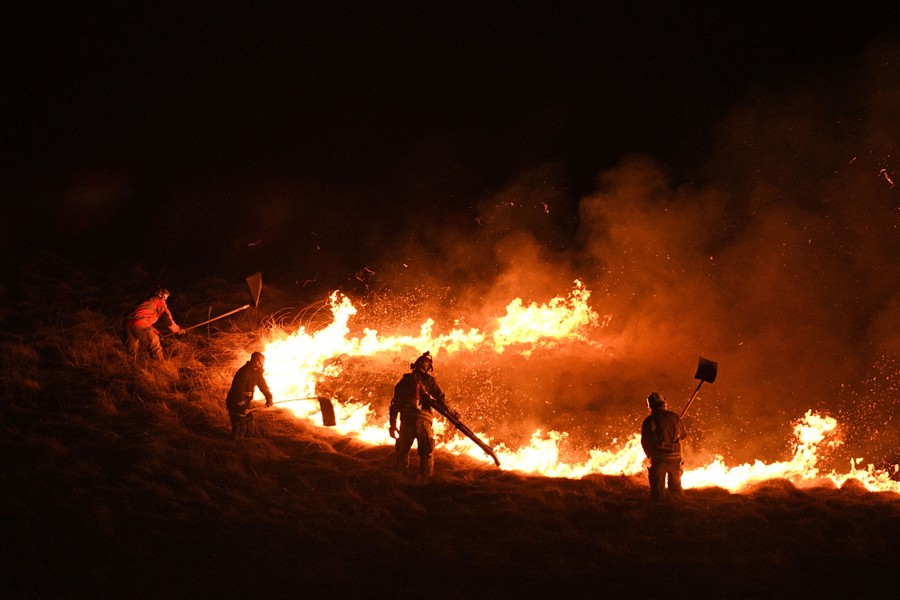 Firefighters battle a broad fire on a moor.