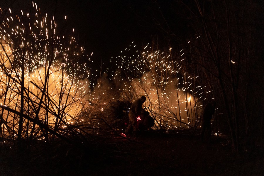 Sparks fly as a piece of artillery is fired at night.