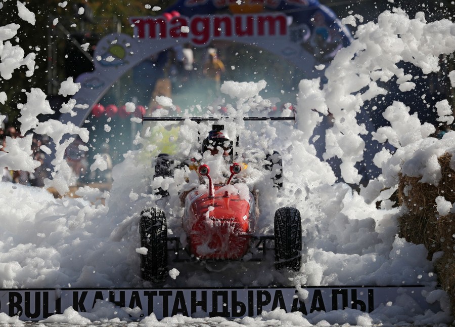 A person steers a homemade vehicle through bubbles on a soapbox derby track.