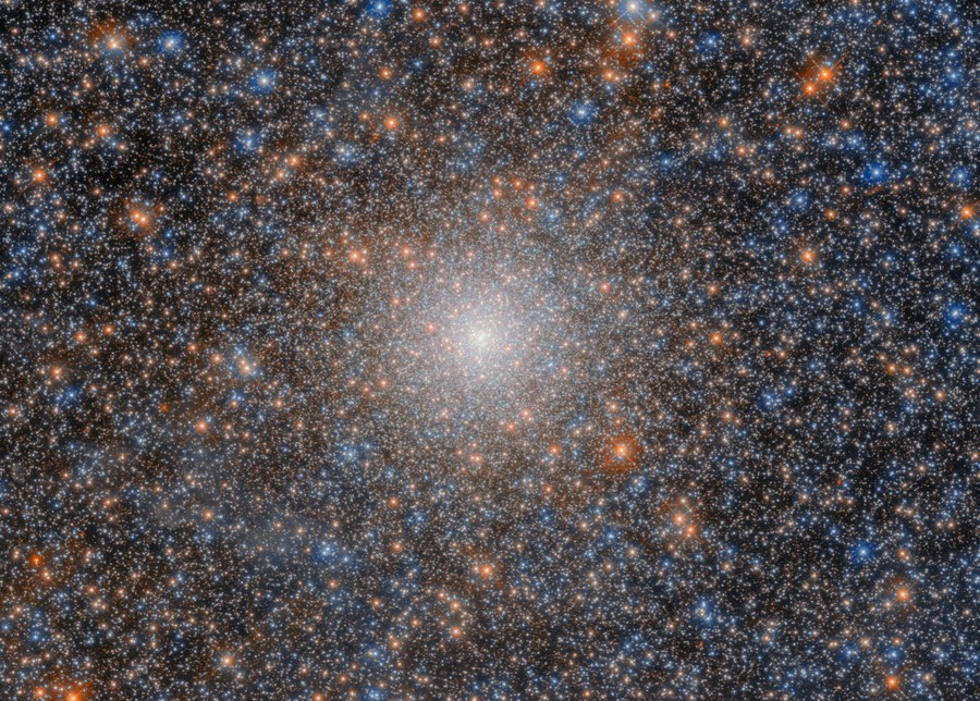 A dense cluster of many thousands of stars, brightening and becoming more dense toward the center of the image