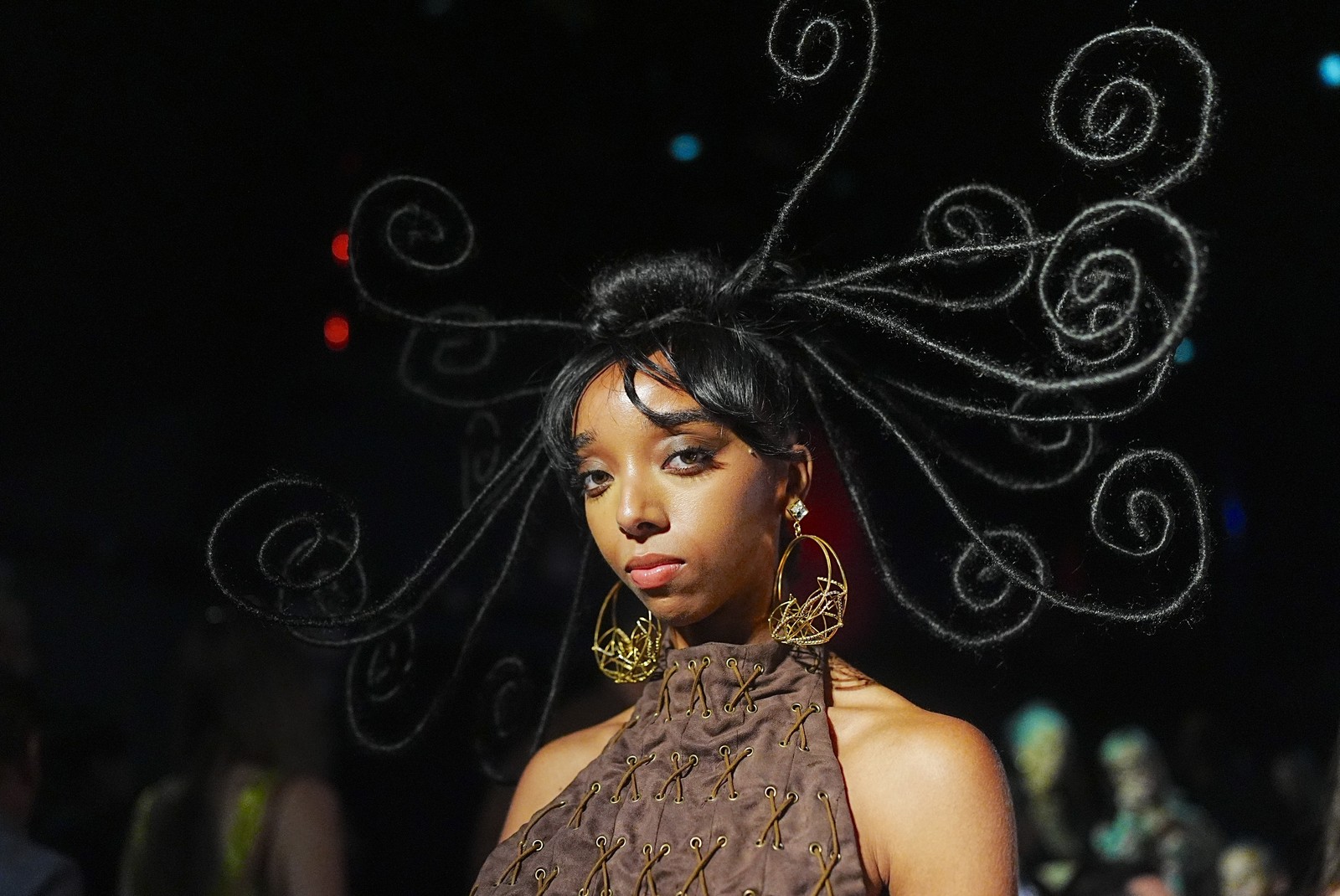 An artist with long and curling hair extensions poses at a fashion show.