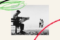 Man reading newspaper while couple is being photographed on the beach
