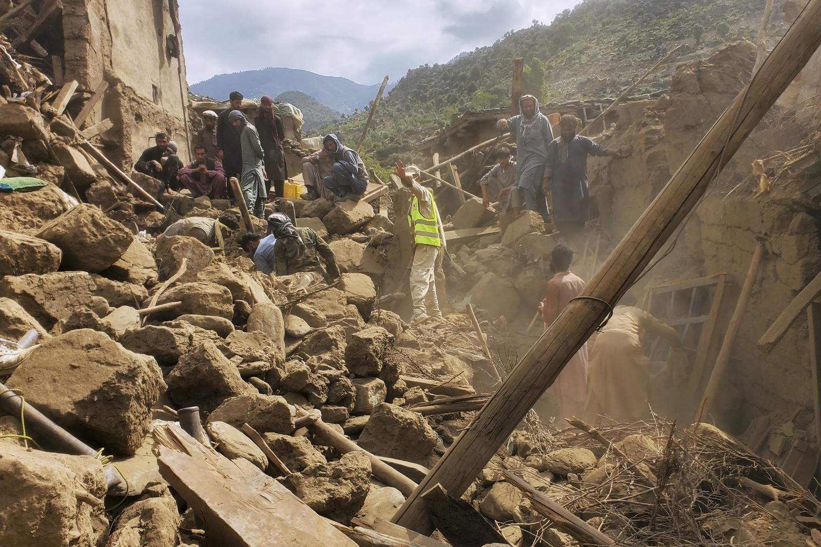 Soldiers and volunteers clear rubble as they search for survivors among destroyed houses.