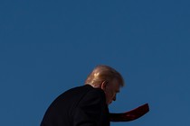 Donald Trump walks away from the camera, his red tie flapping.