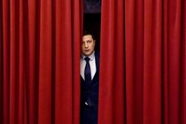 Volodymyr Zelensky as the fictional president of Ukraine, peeking out from behind red curtains, in "Servant of the People"