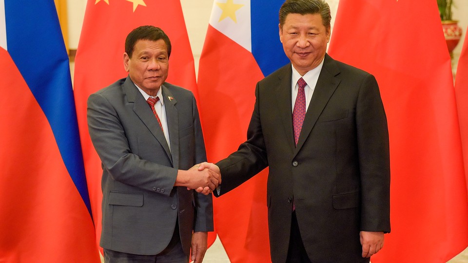 President Xi Jinping shakes hands with Philippines President Rodrigo Duterte in front of Chinese and Filipino flags.
