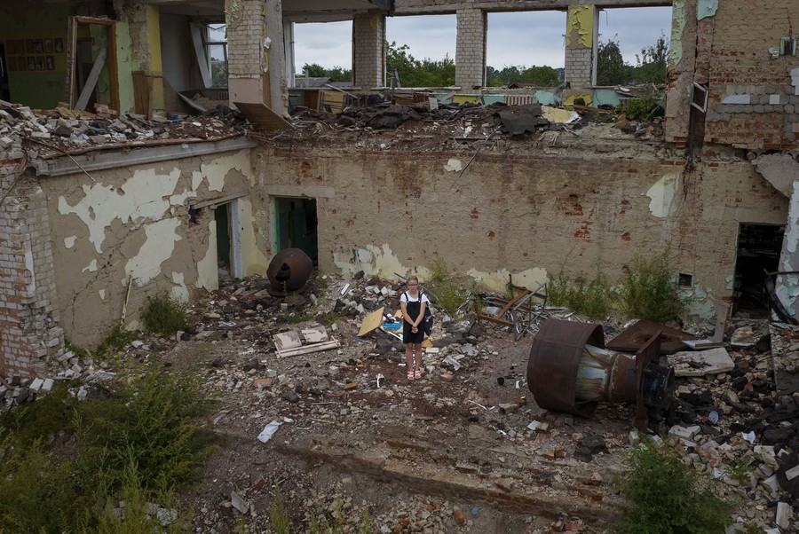 A student stands in the ruins of a destroyed school.