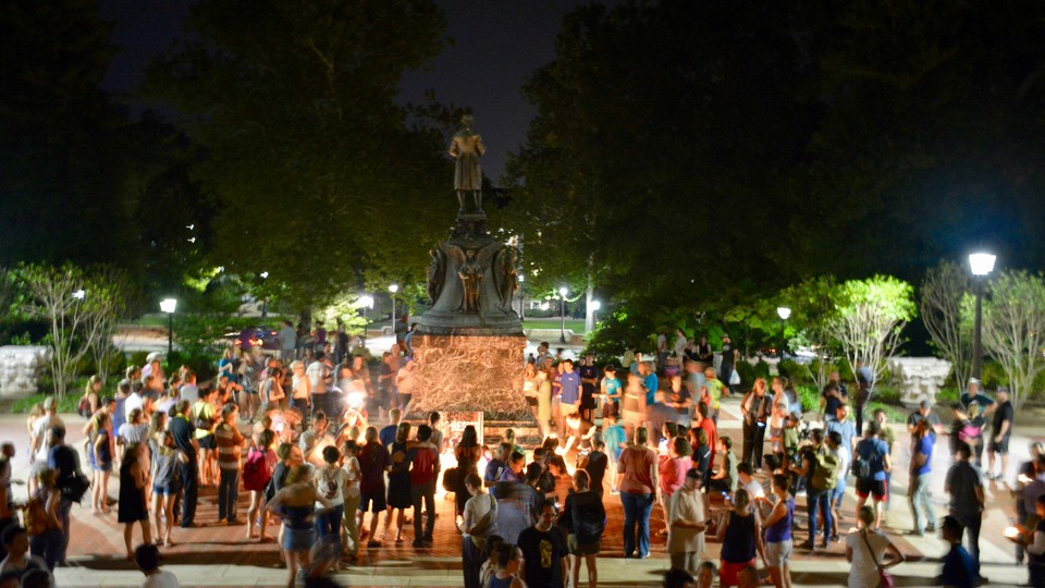 Charlottesville community members are seen leaving candles at the base of a statue of Thomas Jefferson.
