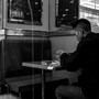 In a black and white image, people sit at different tables in a restaurant.