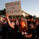 People hold candles at a rally and a woman holds a sign that reads "Enough is enough."