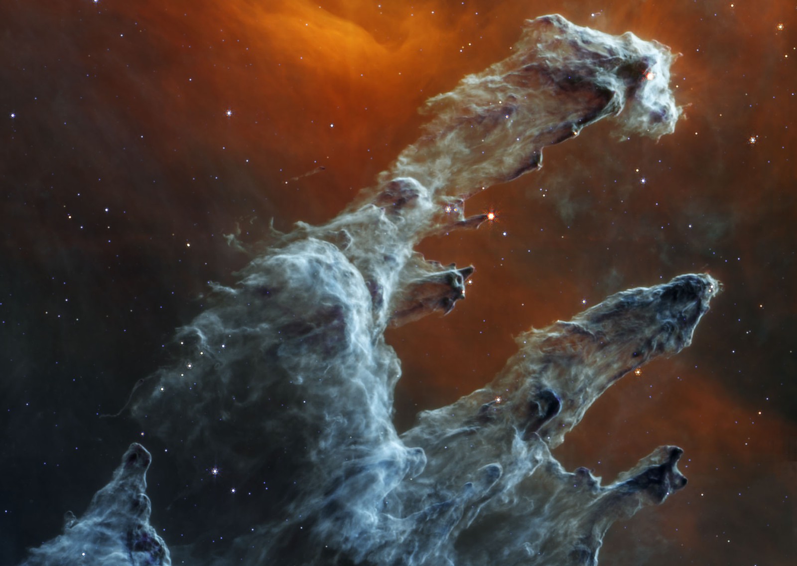 Huge dark pillars of dust and gas, seen against a backdrop of stars