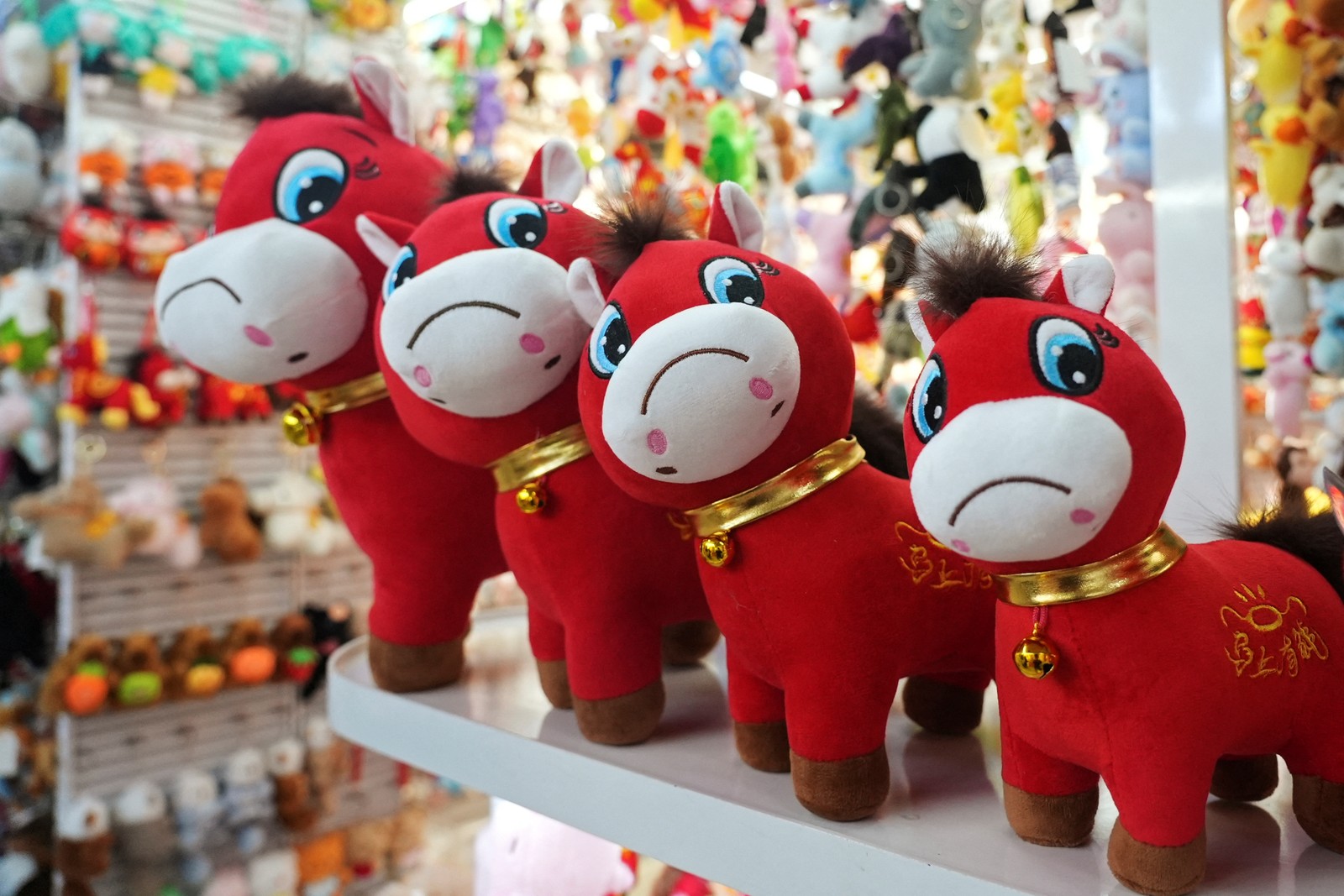 Four plush horse toys, with frowning faces, displayed on a shelf