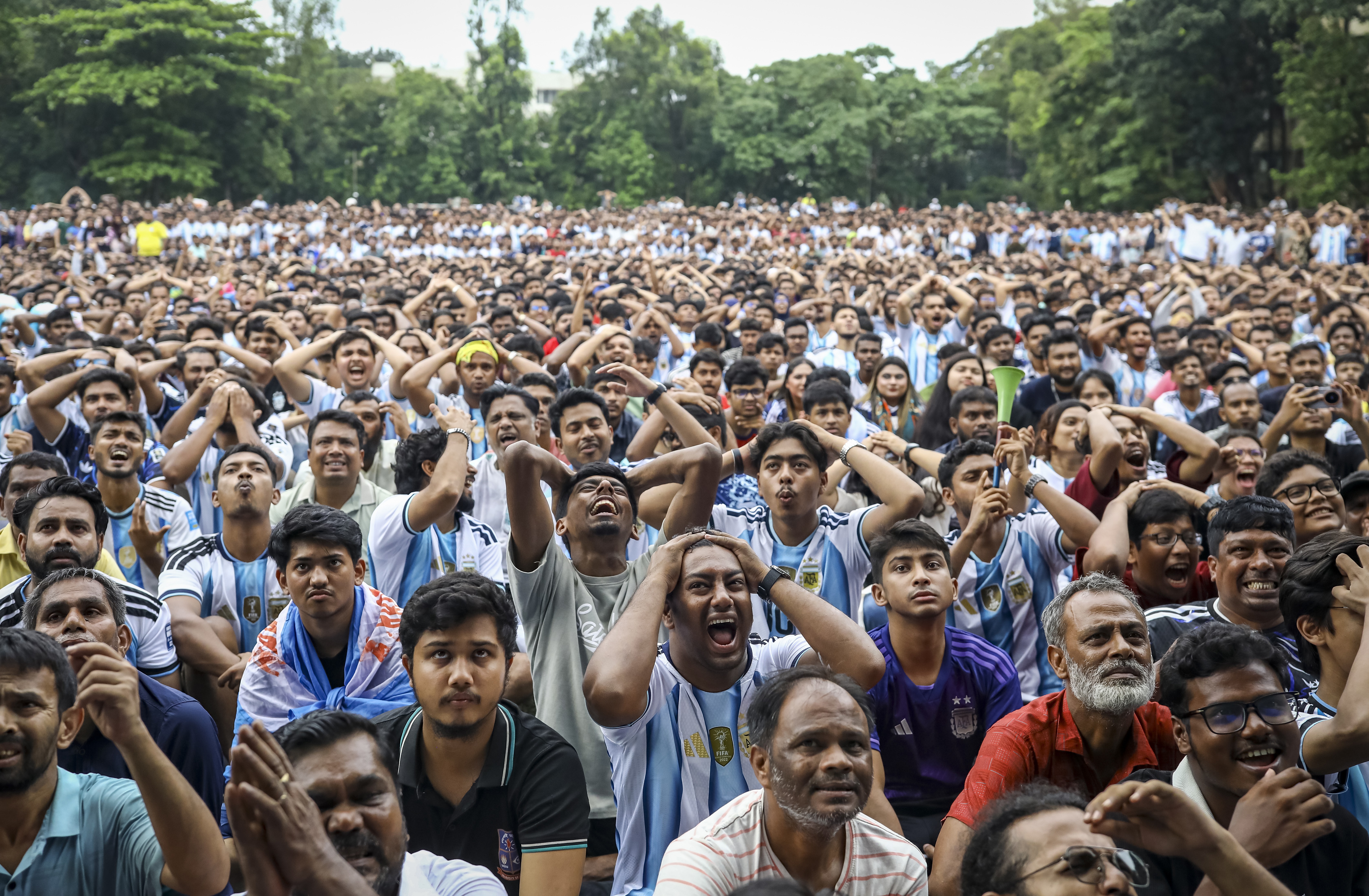 A crowd of soccer fans react during a watch party, many with hands on their heads.