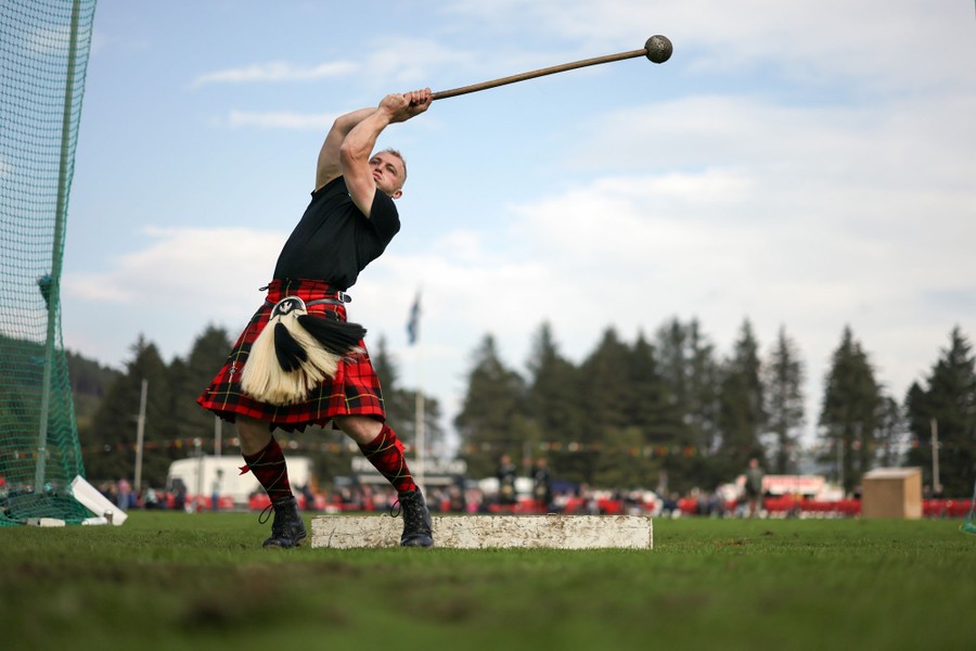 A man in a kilt swings a throwing hammer before releasing it at a Highland Games competition.