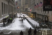 Pedestrians walk down Wall Street in the winter.