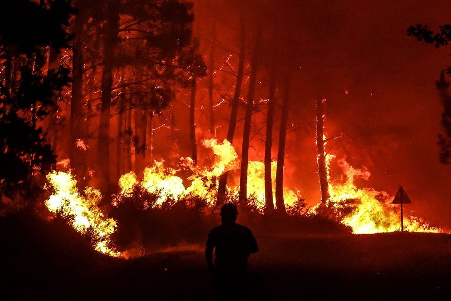 A person walks close to a wildfire at night.