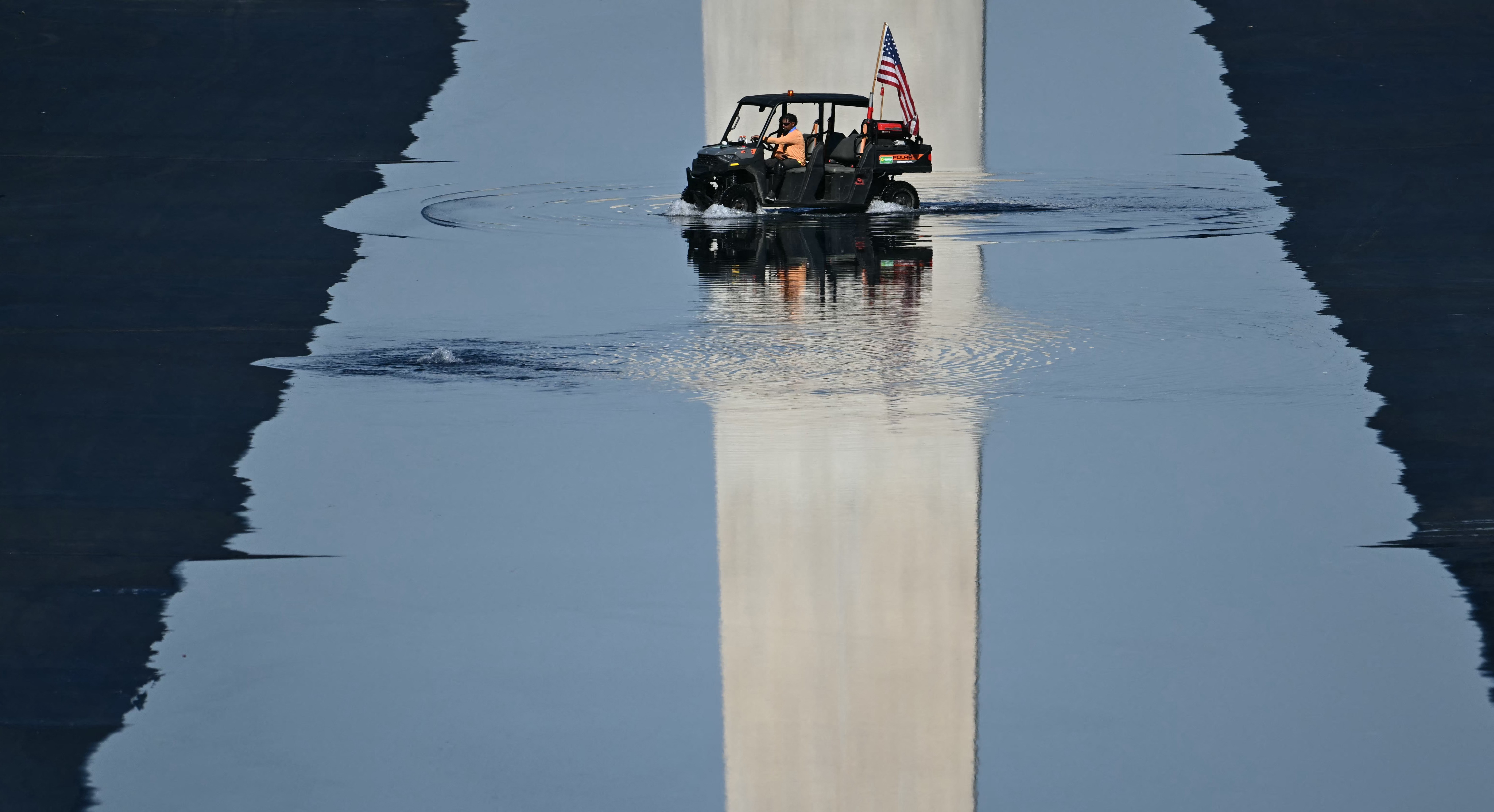 Contractors drive a small vehicle in the partially-filled Lincoln Memorial Reflecting Pool.