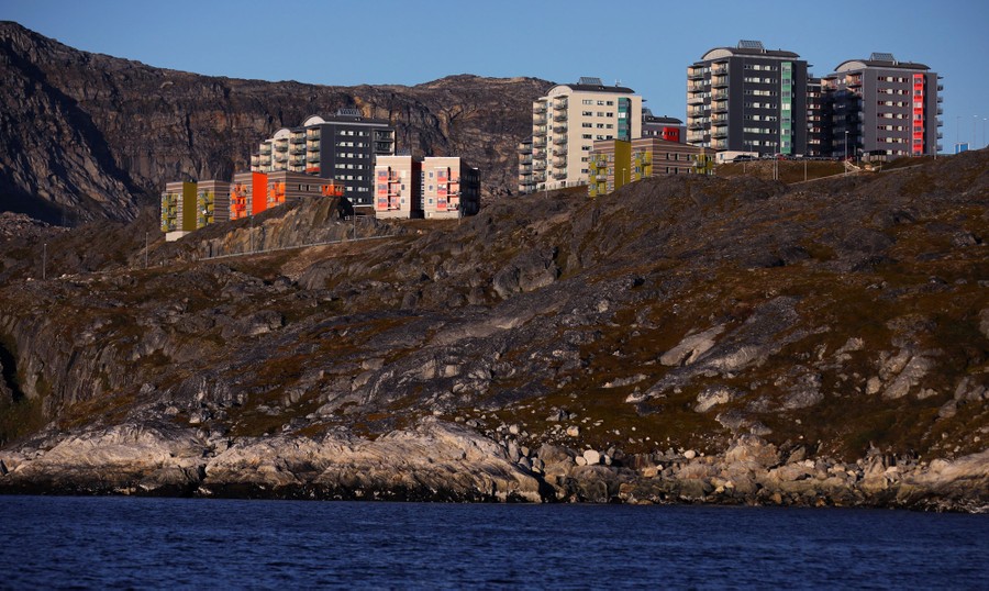 Tall residential buildings stand near a shoreline in Greenland.