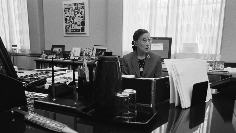 A photograph of Ruth Bader Ginsburg seated at a desk